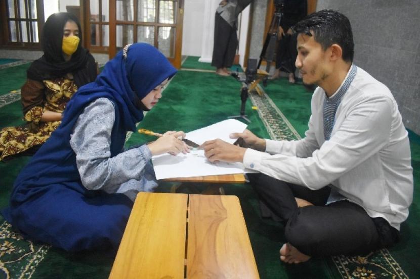 Elfrida Febriola terbiasa dengan pendidikan Islam sejak usia belia. Tampak Febri sedang menandatangani surat sertifikat mualaf di Mualaf Center Malang.