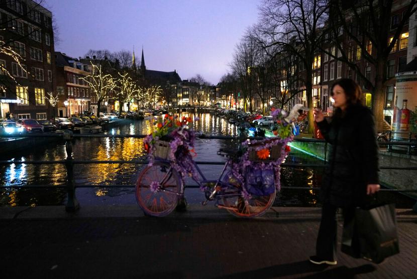 Seorang perempuan melintasi kanal di Amsterdam, Belanda, Sabtu (18/12). Belanda akan melakukan lockdown atau karantina wilayah ketat mulai Ahad (19/12) waktu setempat.