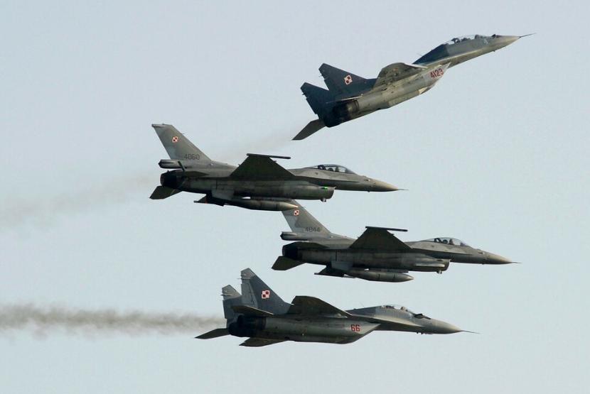 Angkatan Udara Polandia menerbangkan pesawat buatan Rusia MiG-29 (atas) dan jet tempur F-16 selama pameran udara di Radom, Polandia, 27 Agustus 2022. Pemerintah Polandia akan mengerahkan semua jet tempur MiG-29 miliknya ke Ukraina.
