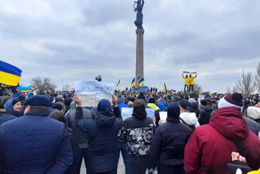 Orang-orang mengibarkan bendera Ukraina selama demonstrasi menentang pendudukan Rusia di Kherson, Ukraina, Sabtu, 5 Maret 2022.