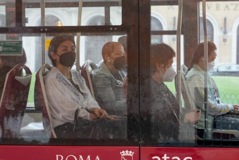 Orang-orang memakai masker saat mereka naik bus angkutan umum di Roma, Ahad, 1 Mei 2022.