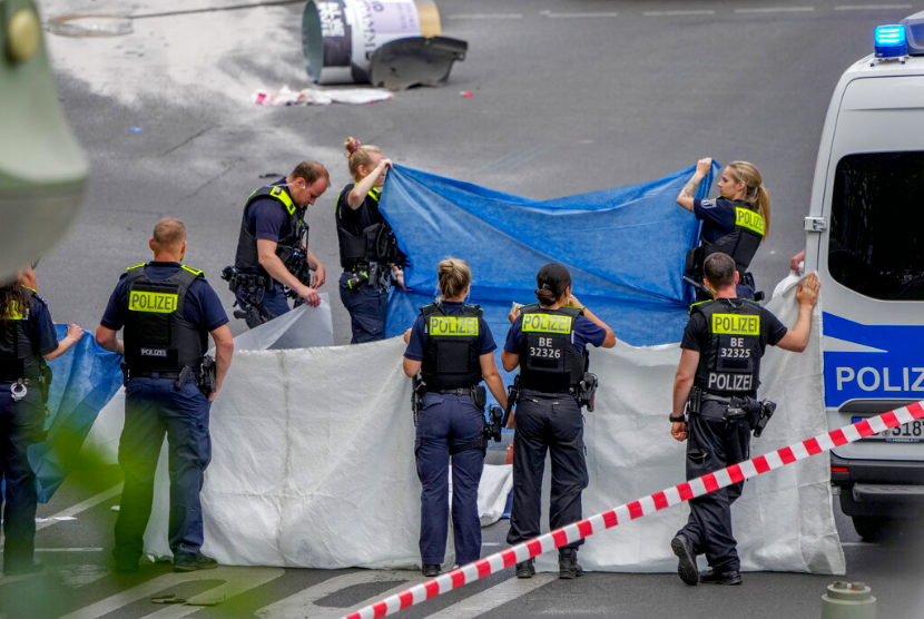 Petugas polisi menutupi mayat setelah sebuah mobil menabrak kerumunan orang di Berlin tengah, Jerman, Rabu, 8 Juni 2022.