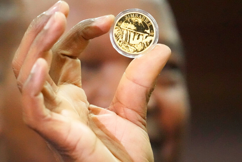 Gubernur Reserve Bank of Zimbabwe, John Mangudya memegang sampel koin emas pada peluncuran di Harare, Senin, 25 Juli 2022. Zimbabwe telah meluncurkan koin emas untuk dijual kepada publik dalam upaya untuk menjinakkan inflasi yang tidak terkendali yang telah semakin mengikis mata uang negara yang tidak stabil.