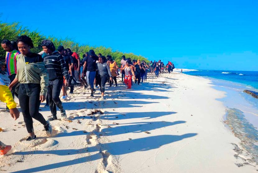 Migran yang diselamatkan berjalan di pantai lepas Pulau Mona, barat Puerto Rico, Kamis, 28 Juli 2022. Pemerintah Meksiko mengatakan pihak berwajib menyelamatkan hampir 100 imigran yang melarikan diri dari kotak trailer sempit yang dibawa penyelundup ke Negara Bagian Veracruz. 