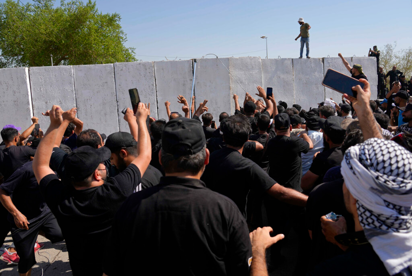 Pendukung ulama Syiah berpengaruh Muqtada al-Sadr mencoba untuk menghapus penghalang beton di daerah Zona Hijau di Baghdad, Irak, Senin, 29 Agustus 2022. Ratusan pengikut al-Sadr, memanjat penghalang semen menuju istana pemerintah Irak setelah dia mengumumkan pengunduran dirinya dari politik pada hari Senin, memicu kekhawatiran akan lebih banyak volatilitas di tengah krisis politik yang belum pernah terjadi sebelumnya.