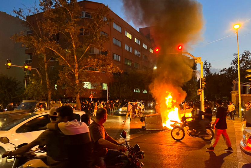 Pada hari Senin, 19 September 2022, foto yang diambil oleh individu yang tidak dipekerjakan oleh Associated Press dan diperoleh AP melihatkan sepeda motor polisi dan tempat sampah dibakar saat protes atas kematian Mahsa Amini, 22 -wanita berusia tahun yang telah ditahan oleh polisi moral bangsa, di pusat kota Teheran, Iran. 