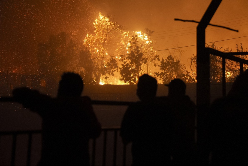 Warga melihat pepohonan yang terbakar ketika api yang bersumber dari area cagar alam Danau Penuelas menjalar ke daerah permukiman di Vina del Mar, Chile, Jumat (2/2/2024).