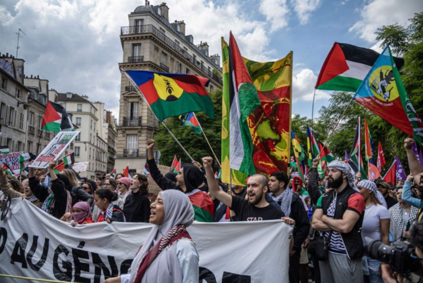 Para pengunjuk rasa mengibarkan bendera komunitas Palestina dan Kanak di Kaledonia Baru saat unjuk rasa di Paris, Prancis, 18 Mei 2024.