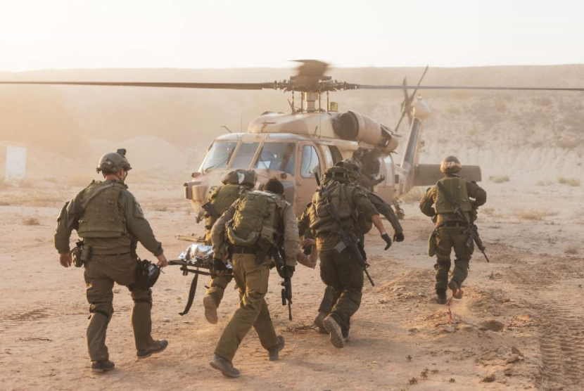 Tentara Israel membawa rekannya yang terluka di Jalur Gaza.