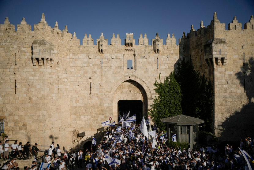 Warga Israel mengibarkan bendera nasional saat pawai memperingati Hari Yerusalem di depan Gerbang Damaskus Kota Tua Yerusalem, Rabu, 5 Juni 2024.