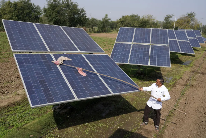 Petani di India membersihkan panel surya yang terpasang di lahan pertanian, Januari 2023.