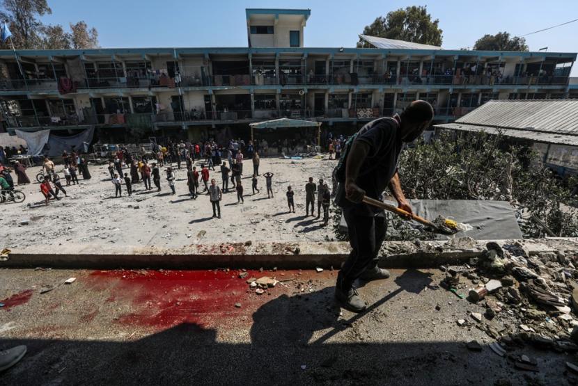 Seorang warga Palestina membersihkan puing-puing di sekolah UNRWA yang hancur akibat serangan udara Israel di Nusairat di Jalur Gaza, 6 Juni 2024. Bom buatan India disebut dipakai Israel dalam serangan itu.