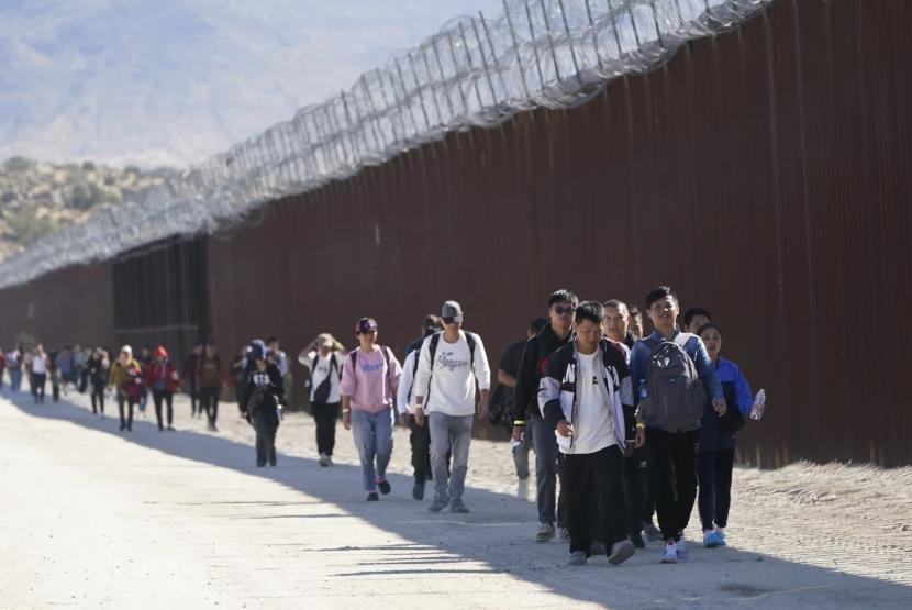 Sejumlah imigran gelap termasuk dari Cina berbaris di dekat pagar perbatasan AS-Meksiko di Jacumba, Kalifornia pada Oktober 2023 lalu.
