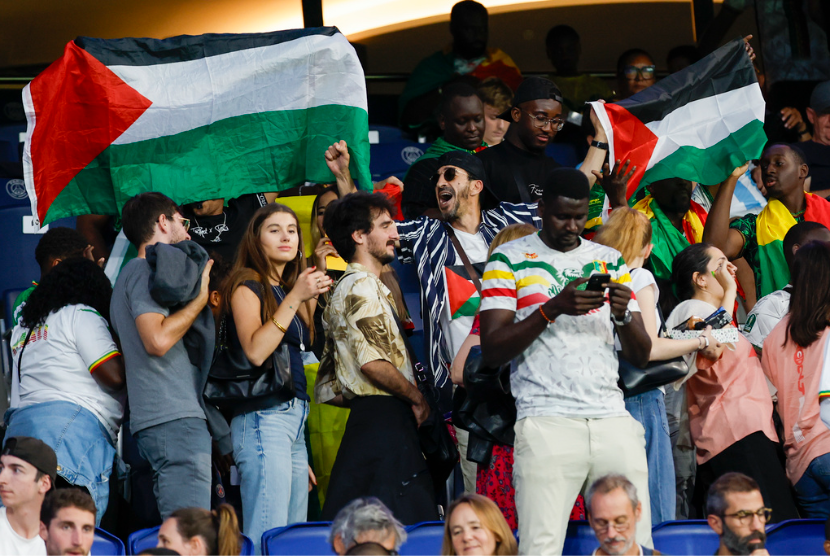 Penonton mengibarkan bendera Palestina saat menyaksikan pertandingan antara Israel dan Mali di Parc des Princes saat Olimpiade 2024, Rabu, 24 Juli 2024, di Paris, Prancis.