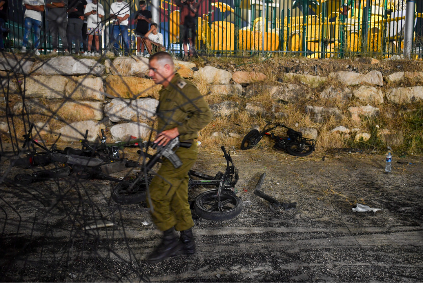 Tentara Israel melintasi area yang terkena roket yang menewaskan banyak anak dan remaja di lapangan sepak bola di kota Druze Majdal Shams, di Dataran Tinggi Golan yang dianeksasi Israel, Sabtu, 27 Juli 2024. 