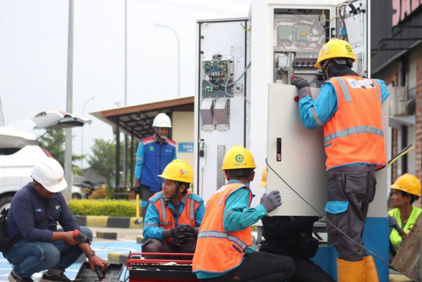 Petugas PLN tengah melakukan pemasangan dan pengintegrasian SPKLU di rest area ruas tol Mojokerto-Surabaya.