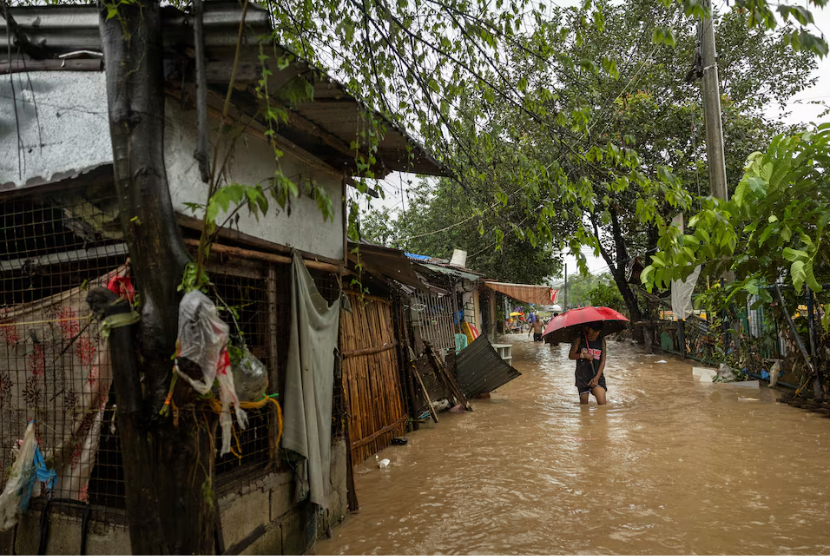  Seorang pria berjalan menerobos banjir setelah hujan lebat yang disebabkan Badai Tropis Yagi, di Baras, Provinsi Rizal, Filipina, Senin (2/9/2024).