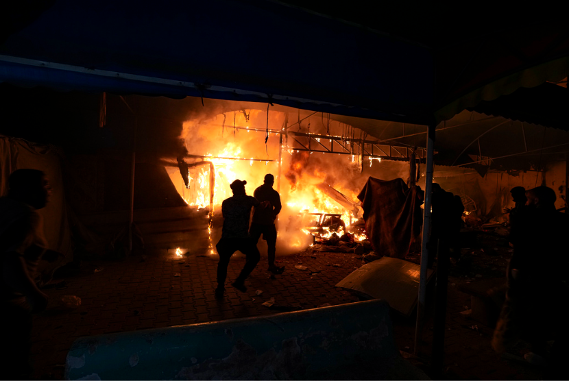 Warga menyaksikan kebakaran setelah serangan Israel menghantam area tenda di halaman rumah sakit Syuhada Al Aqsa di Deir al-Balah, Jalur Gaza, Senin, 14 Oktober 2024.