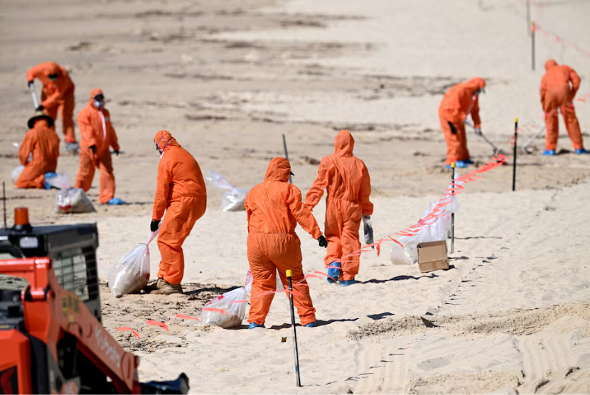 Pekerja dengan pakaian pelindung membersihkan puing-puing misterius yang terdampar di Pantai Coogee, Sydney, Australia, Kamis (17/10/2024).