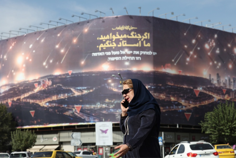 Seorang wanita Iran berjalan di dekat papan iklan anti-Israel di alun-alun Enghelab di Teheran, Iran, 26 Oktober 2024.