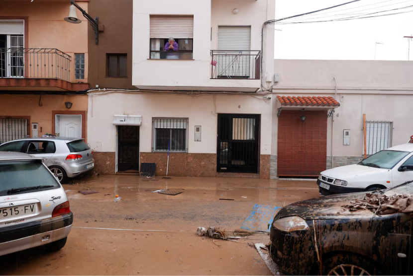 Seorang wanita melihat kondisi jalanan yang tertutup lumpur setelah hujan lebat yang menyebabkan banjir di La Alcudia, wilayah Valencia, Spanyol, Rabu (30/10/2024). 