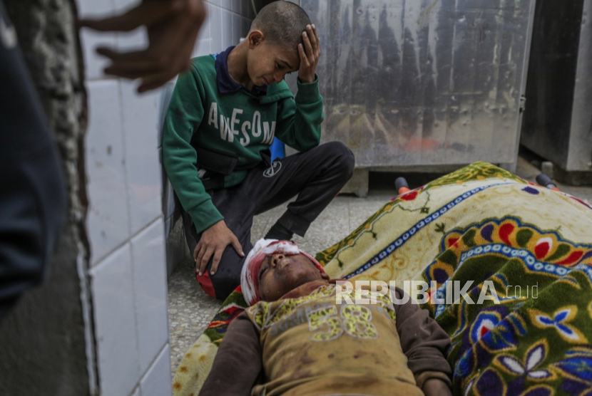 Ismail Faraj berduka atas jenazah saudaranya Shadi (14 tahun) di Rumah Sakit al-Aqsa, menyusul serangan Israel di kamp pengungsi Bureije, Jalur Gaza tengah, 4 Desember 2024.