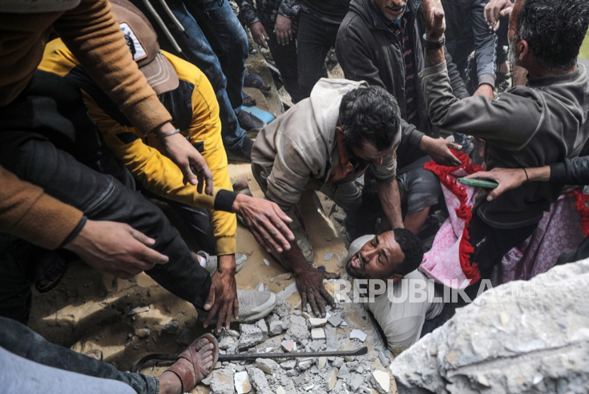 Warga Palestina mencari jenazah dan korban selamat di antara puing-puing rumah yang hancur akibat serangan udara Israel di kota Deir Al Balah, selatan Jalur Gaza, 18 Februari 2024.