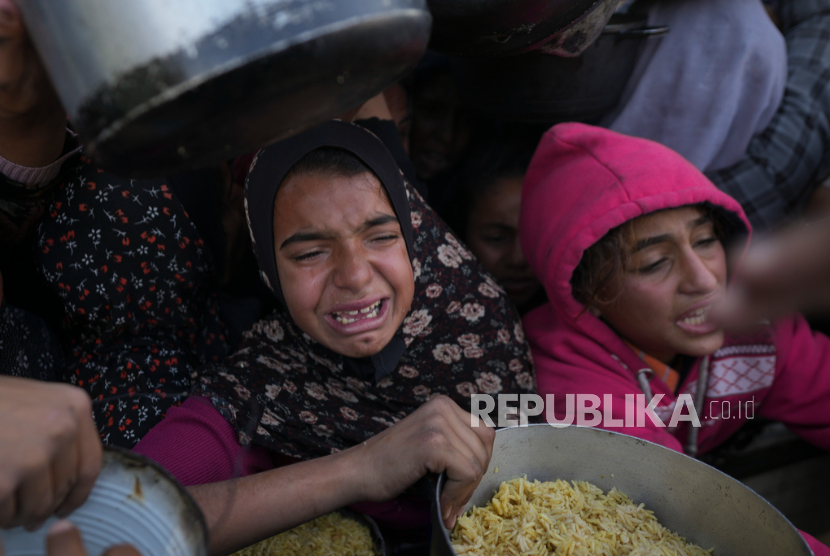 Gadis-gadis Palestina berjuang untuk mendapatkan makanan di pusat distribusi di Khan Younis, Jalur Gaza Jumat, 6 Desember 2024.  Agresi Israel telah menyebabkan kelaparan parah di Jalur Gaza.