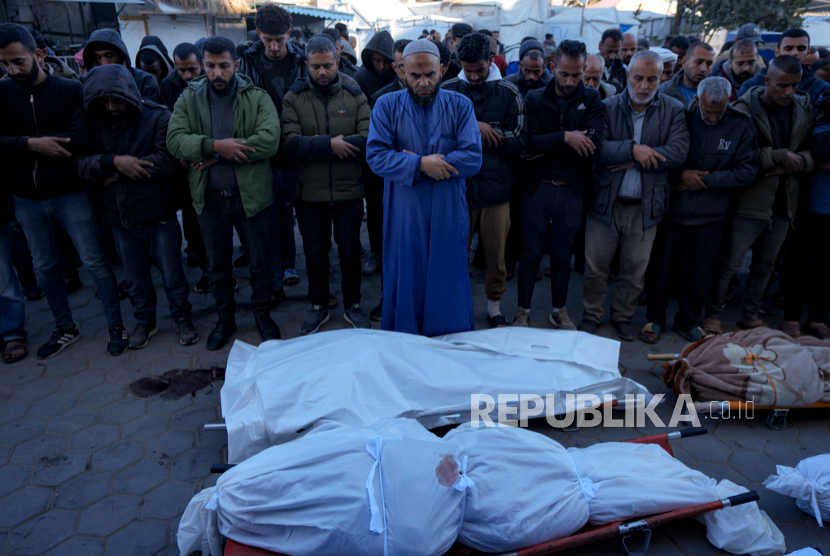 Warga Palestina berdoa di samping jenazah kerabat mereka yang tewas dalam pemboman Israel di Jalur Gaza, di sebuah rumah sakit di Deir al-Balah, Ahad, 15 Desember 2024.