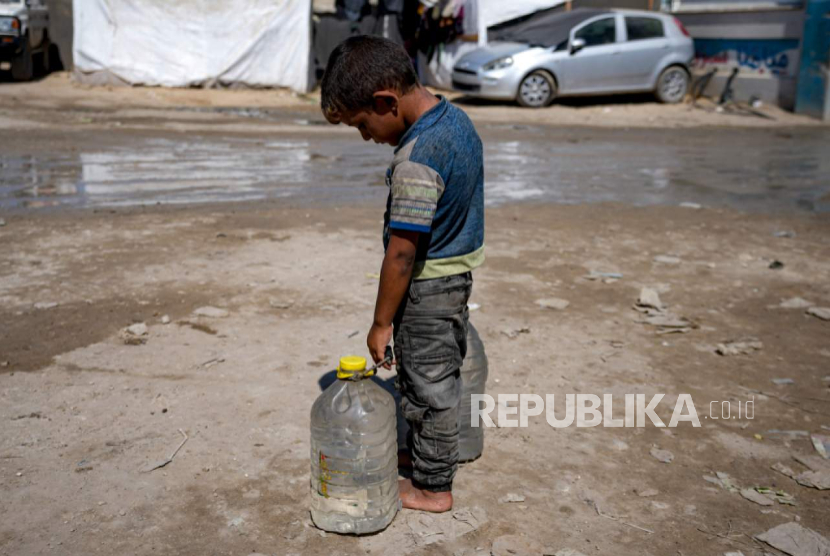 Anak pengungsi membawa botol air berisi air di tenda darurat di Deir al-Balah, Jalur Gaza tengah, Kamis, 29 Agustus 2024. 