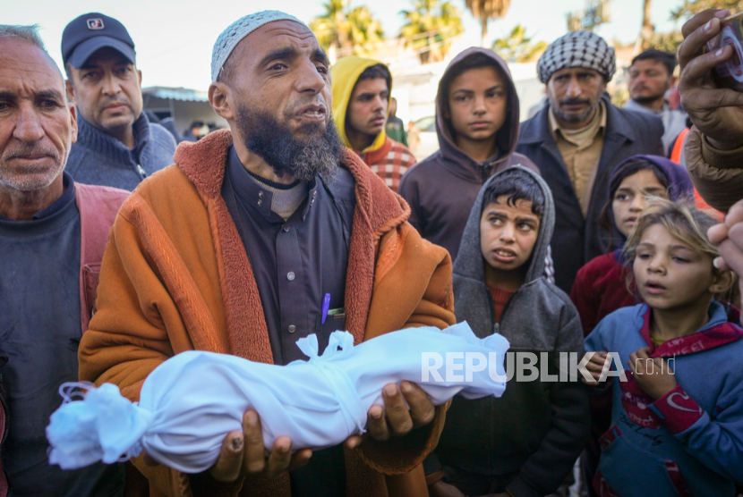 Imam Islam Abu Suaied menggendong jenazah Juma Al-Batran bayi berusia sebulan yang meninggal kedinginan di Deir al-Balah, Gaza, Ahad, 29 Desember 2024.