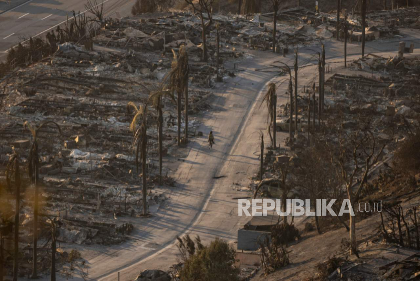 Seseorang berjalan melalui lingkungan yang hancur akibat Kebakaran di bagian Pacific Palisades di Los Angeles, Jumat, 10 Januari 2025. 