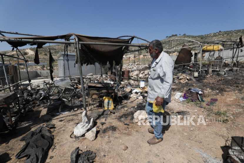 Seorang pria Palestina memeriksa bangunan yang terbakar pemukim Israela di desa Al-Mughayyir, Tepi Barat, dekat Ramallah (ilustrasi)