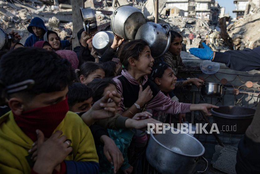 Anak-anak pengungsi Palestina antri untuk menerima porsi makanan dari dapur amal sebelum berbuka puasa, di Beit Lahia, Jalur Gaza utara, 10 Maret 2025.