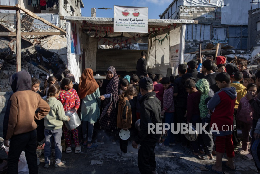 Anak-anak pengungsi Palestina berbaris untuk menerima sebagian makanan dari dapur amal sebelum berbuka puasa, di Beit Lahia, Jalur Gaza utara, 10 Maret 2025.