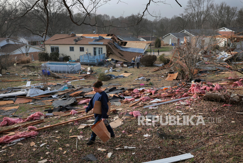 Warga berjalan di tumpukan puing di belakang rumah kerabatnya setelah badai hebat di Bridgeton, Missouri, Sabtu, 15 Maret 2025. (Robert Cohen/St. Louis Post-Dispatch via AP)