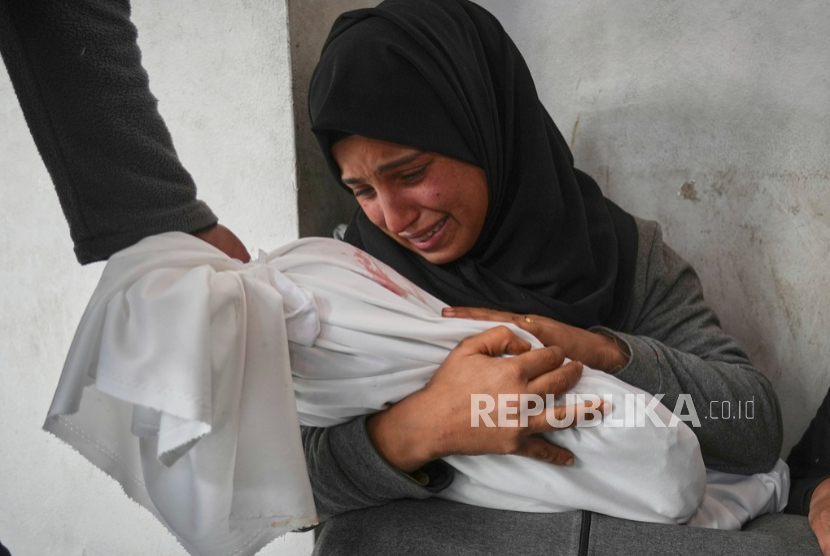 Amani Abu Aker memegang jenazah keponakannya yang berusia dua tahun, Salma, yang syahid dalam serangan tentara Israel di Kota Gaza, Senin 24 Maret 2025.