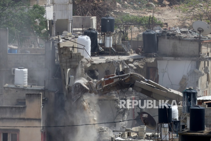 Sebuah ekskavator tentara Israel menghancurkan bangunan selama operasi militer Israel di kamp pengungsi Nur Shams, dekat kota Tulkarem, Tepi Barat, 5 Mei 2025.