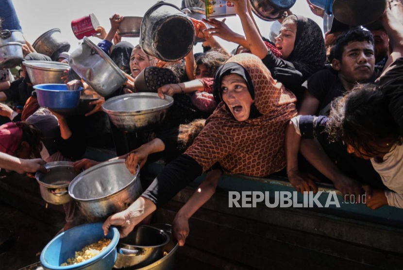 Warga Palestina berjuang untuk mendapatkan sumbangan makanan di dapur komunitas di Khan Younis, di selatan Jalur Gaza, Jumat, 9 Mei 2025.