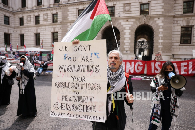 Seorang pengunjuk rasa memegang plakat dan bendera Palestina saat melakukan protes di luar Kantor Luar Negeri dan Persemakmuran di London, Inggris, 21 Mei 2025.