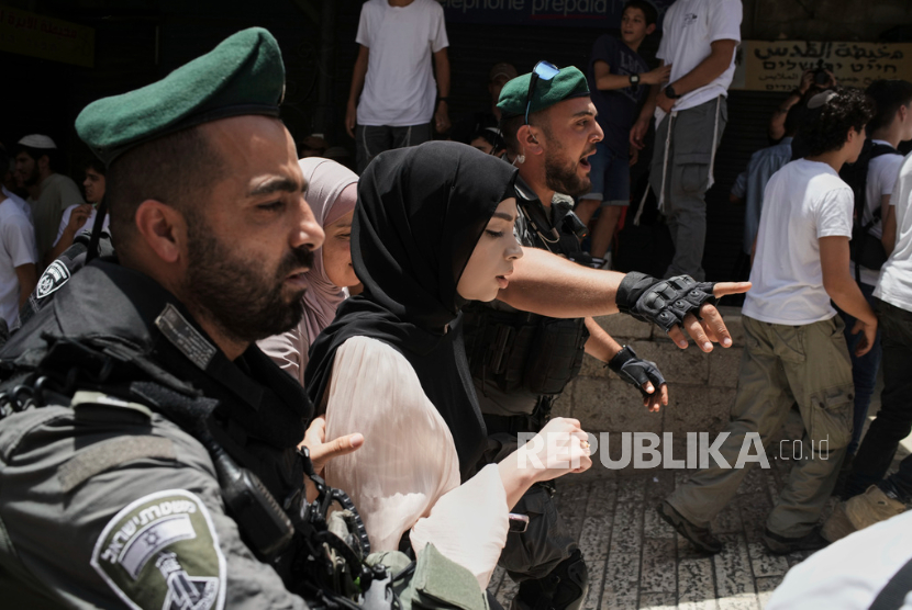 Petugas polisi Israel mengawal wanita Palestina saat warga Israel memperingati Hari Yerusalem, di Kota Tua Yerusalem, Senin, 26 Mei 2025.