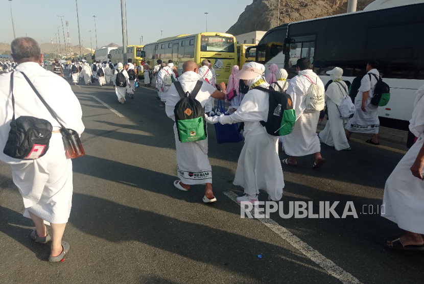 Sebagian jamaah haji Indonesia memilih berjalan kaki dari Muzdalifah ke Mina karena arus lalu lintas yang sangat padat, Jumat (6/6/2025). Jamaah dari berbagai negara lain juga berjalan kaki di samping bus yang mandek tak bisa bergerak.