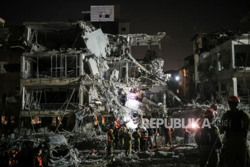Petugas tanggap darurat Israel bekerja di lokasi yang terkena serangan rudal dari Iran di Ramat Gan, Israel, Sabtu (14/6/2025).