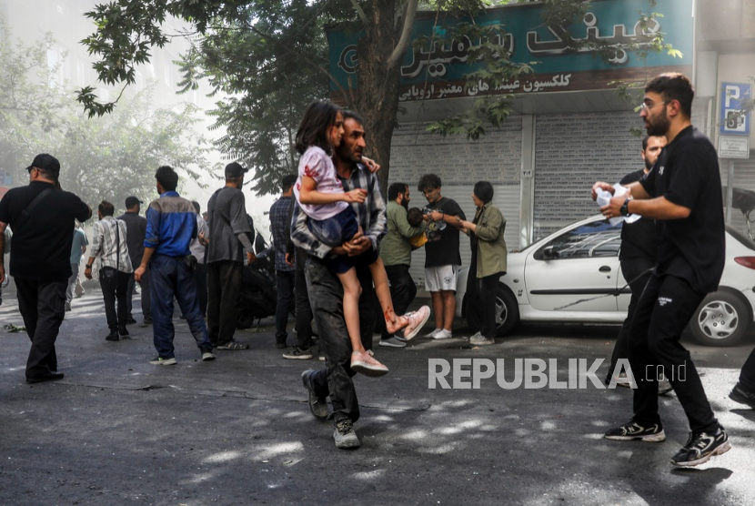 Anak-anak korban serangan Israel dibantu meninggalkan lokasi kejadian setelah ledakan di pusat kota Teheran, Ahad, 15 Juni 2025.
