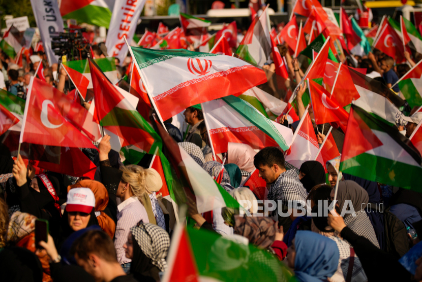 Orang-orang mengibarkan bendera Palestina, Turki, dan Iran saat protes di Istanbul, Turki.