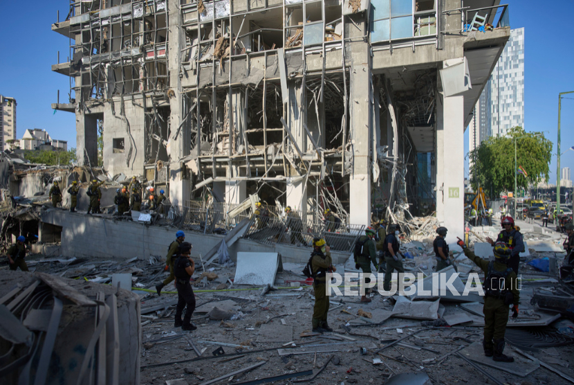 Petugas dan personel militer memeriksa lokasi serangan langsung serangan rudal Iran di Ramat Gan, Israel, Kamis, 19 Juni 2025.