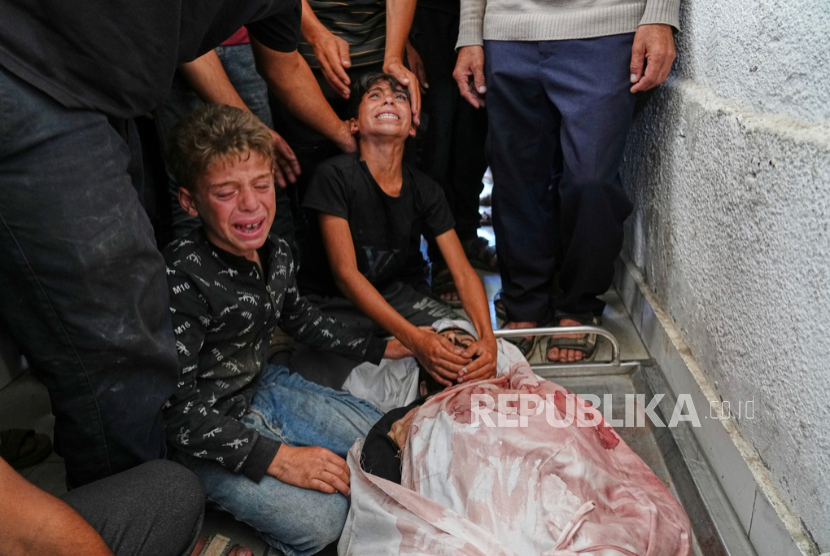 Anak-anak Palestina berduka atas jenazah ayah mereka yang terbunuh saat menuju pusat distribusi bantuan, di kamar mayat Rumah Sakit Shifa di Kota Gaza, Rabu, 18 Juni 2025. 