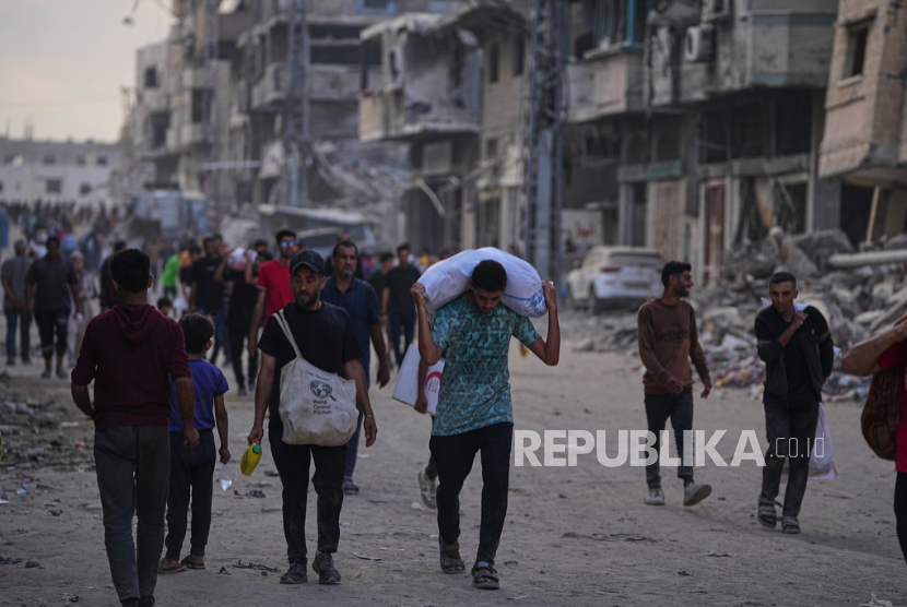 Warga Palestina membawa karung makanan dan bantuan kemanusiaan yang diturunkan dari konvoi truk menuju Kota Gaza, di Jalur Gaza utara, Ahad, 22 Juni 2025.