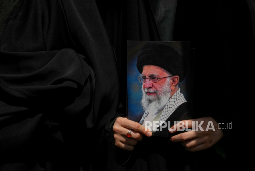 Seorang pengunjuk rasa memegang poster Pemimpin Tertinggi Iran Ayatollah Ali Khamenei di Teheran, Iran, Jumat, 20 Juni 2025.