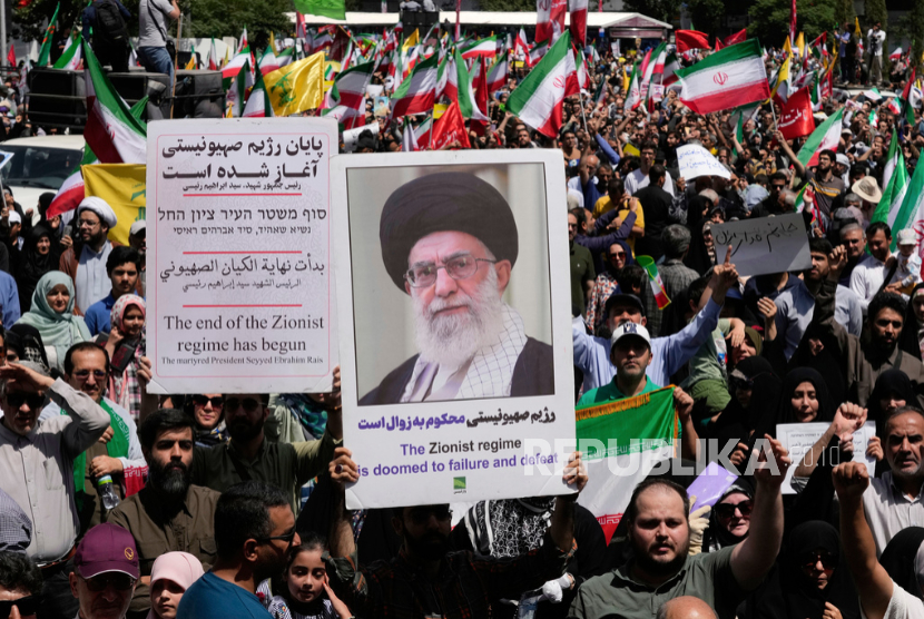 Seorang pengunjuk rasa memegang poster Pemimpin Tertinggi Iran Ayatollah Ali Khamenei di Teheran, Iran, Jumat, 20 Juni 2025.